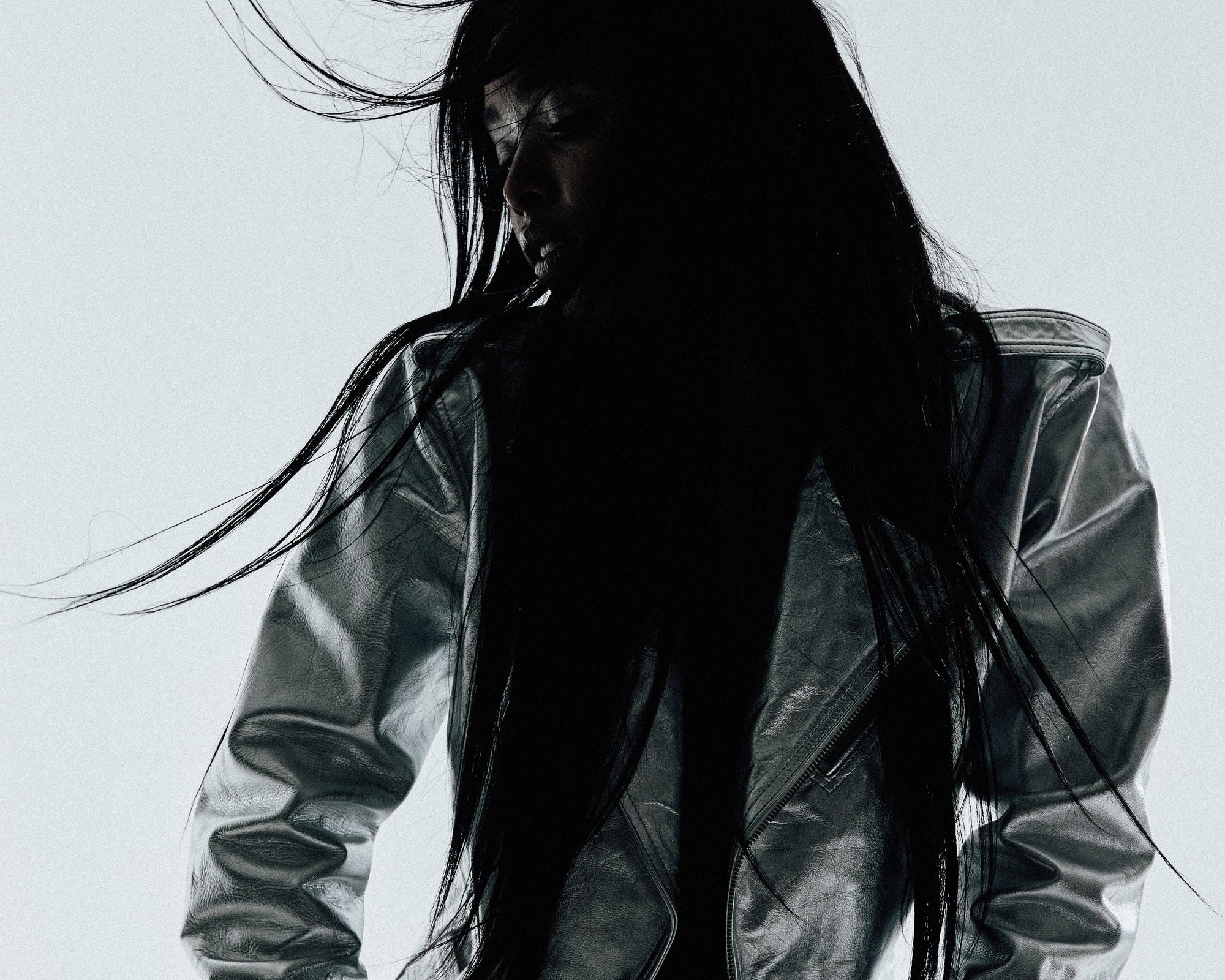 Person wearing a reflective silver jacket sitting on a white surface with a light gray background